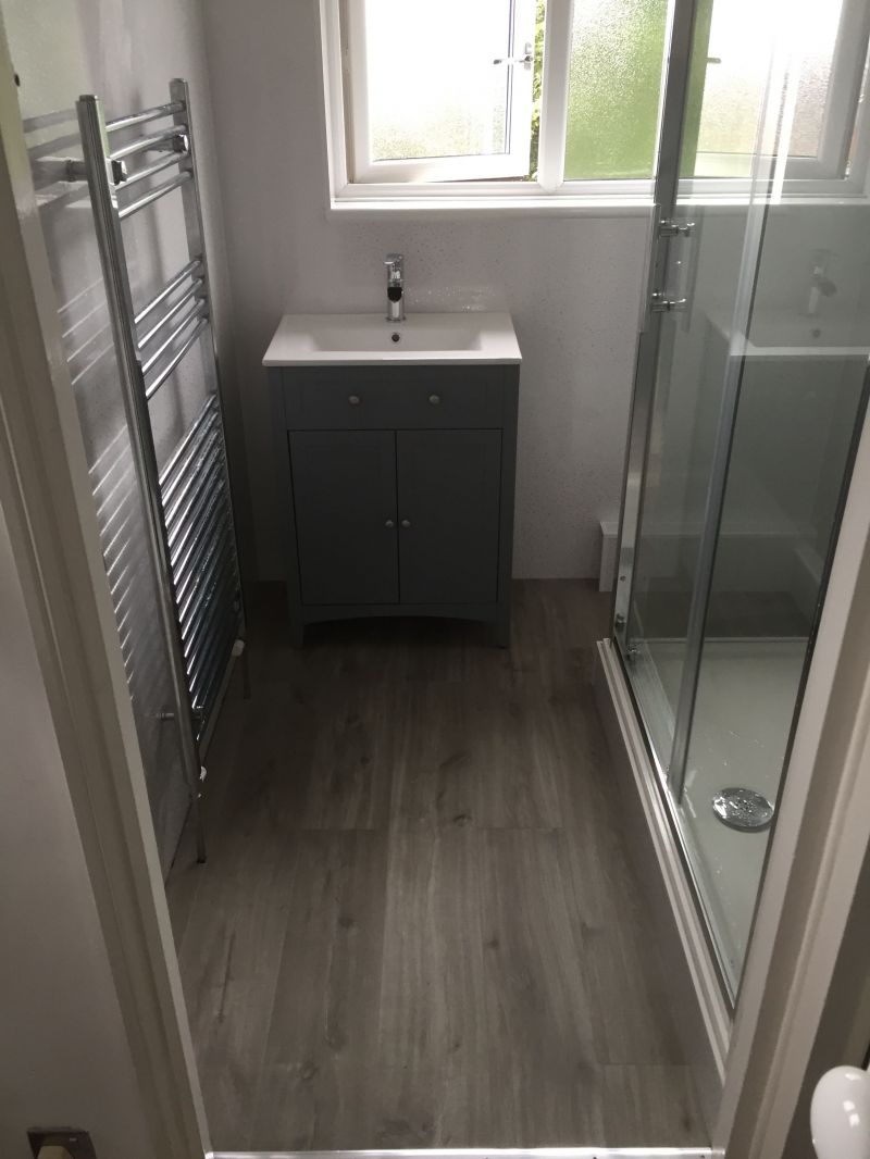 White Sparkle on the main bathroom walls and a contrasting grey sparkle in the shower!

A new shower tray, glass door and side panel with chrome trim, electric shower, and toilet supplied and fitted together with customers own Vanity unit & basin. A Light Grey Vinyl Click flooring fitted in bathroom and separate toilet area. : Swipe To View More Images
