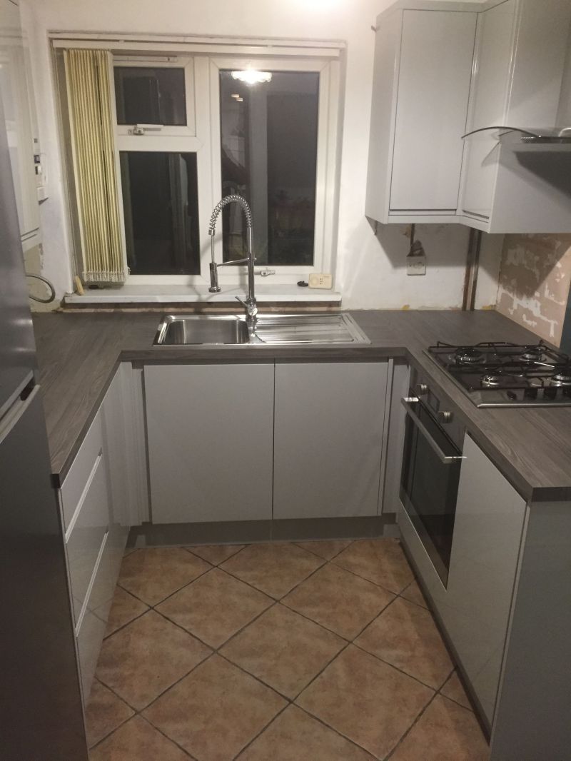 Homebase Gloss Grey Handleless Kitchen range with Ink Bark worktop and Indesit appliances.: Swipe To View More Images