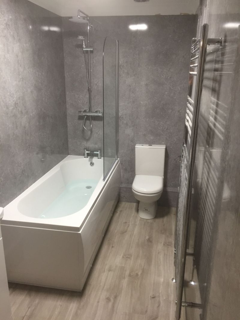 Shower Bath and suite with Grey concrete effect wetwall throughout.  : Swipe To View More Images