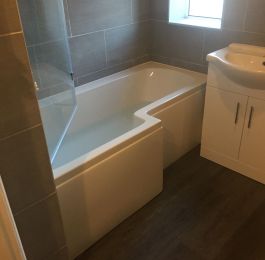 Bath & Shower Room, L Shaped Bath with double headed shower, glass shower screen, vanity unit, close couple toilet.  Inara concrete tiles, Dark Grey vinyl click flooring & chrome raditor towel rail.: Click Here To View Larger Image