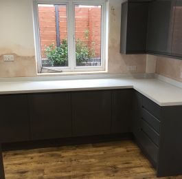 Howdens Clerkenwell Kitchen Super Matt integrated handle door in Graphite with Storm Grey Quartzstone worktops and upstands with a contrasting Vinyl Click flooring in Chestnut.: Click Here To View Larger Image